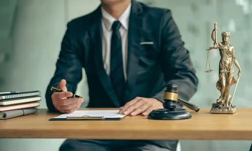 A motorcycle accident lawyer behind his desk, filling up a form for his client.