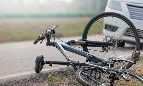 A dark blue bicycle knocked off a suburban road after a collision with a white vehicle.