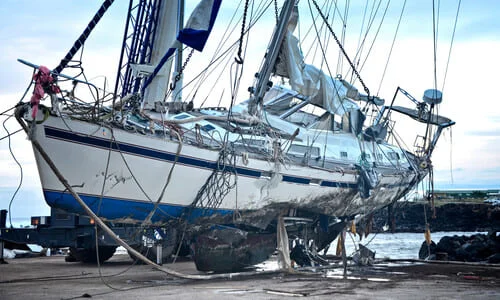 A boat with a hole in its side resting at a pier, after an accident that sunk it.