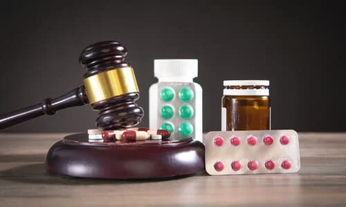 A gavel and soundblock resting on a table, next to several blister packets and bottles of pills.