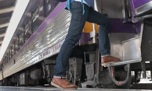 A low-to-the-ground shot of a passenger getting on board a train at a station.