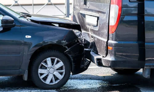 A rear-end collision between a black sedan and a black van.