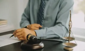 A lawyer in a grey shirt holding a pen over documents he is studying for a client's insurance claim.