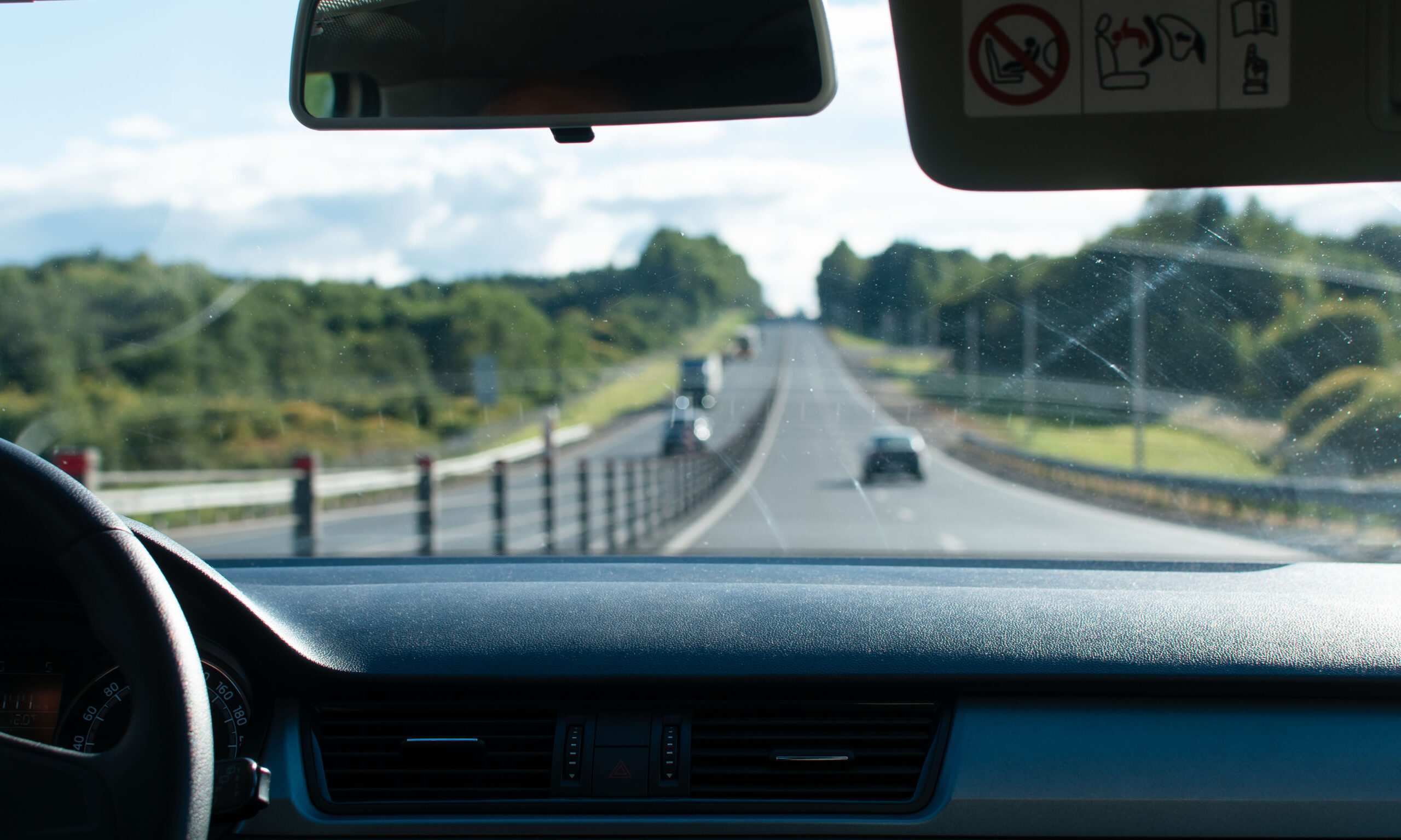 A driver's view of a highway drive with cars in the distance.