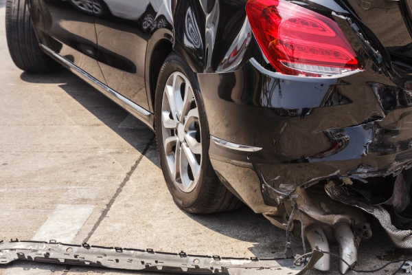 A black car's crumpled back end damaged by a collision with another vehicle.