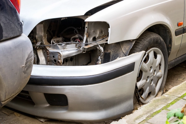 A white car whose headlight popped out after crashing into the rear end of another vehicle.