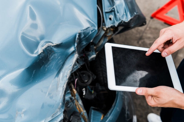 An accident victim tallying damage to her car on a tablet after a crash.