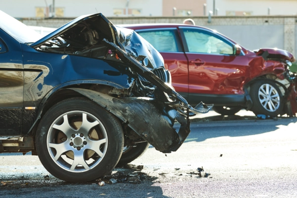 Two vehicles, one black and one red, stopped on a road after crashing into each other.