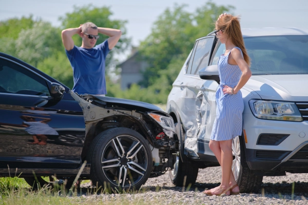 Two drivers on a road looking at the collision between their two vehicles.