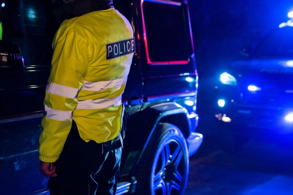 A police officer checking the driver of an SUV after an accident on a suburban road at night.