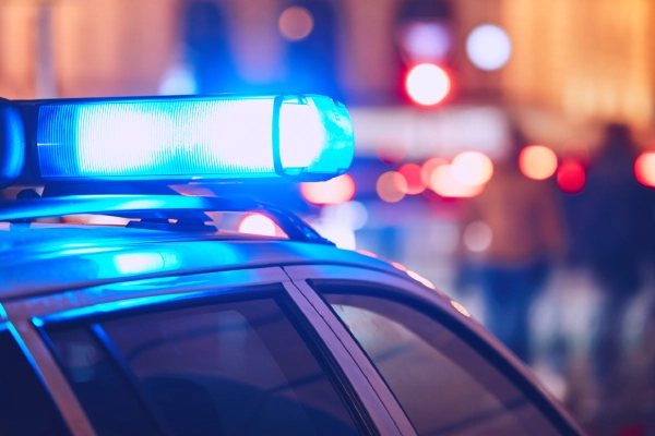 The blue flasher of a police car in a city at night time at the scene of an accident.