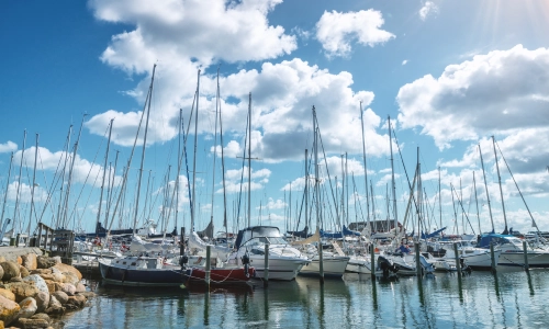 A dock with many small sailboats docked on a partially cloudy day.