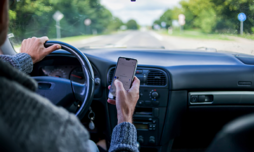 Distracted driver using a phone behind the wheel, a common case handled by a car accident lawyer.
