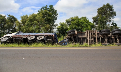 An overturned truck is lying across the highway after an accident.