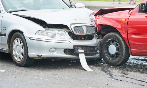 A silver sedan and a red hatchback bumped into each other on the street.