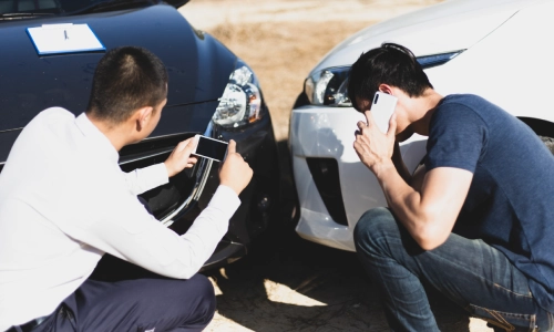 Two men are inspecting the damage to cars that have collided. 